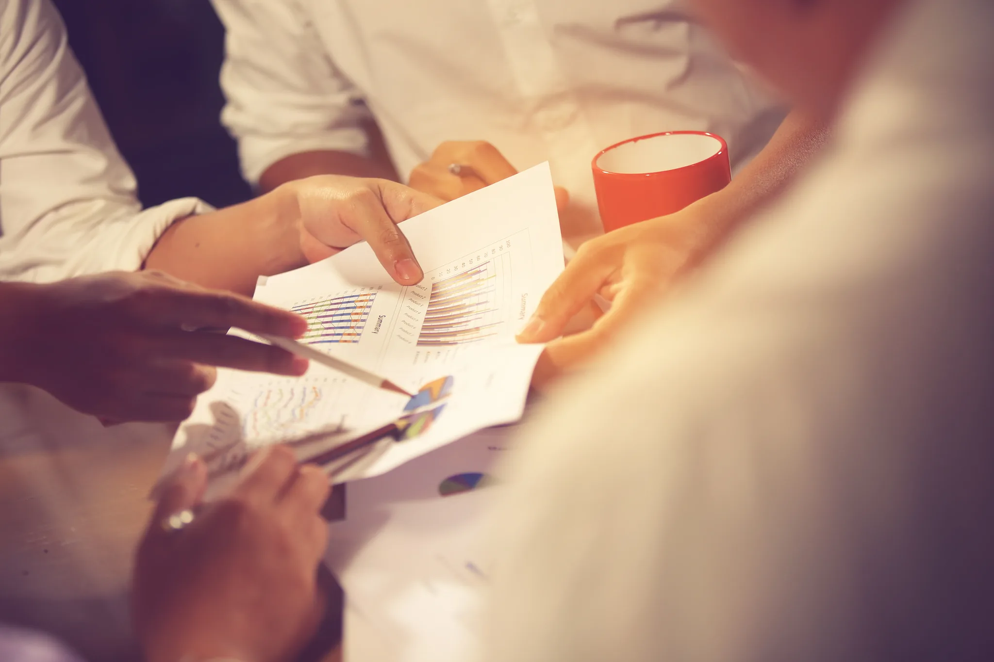 Plusieurs mains désignent des graphiques sur des documents lors d'une réunion