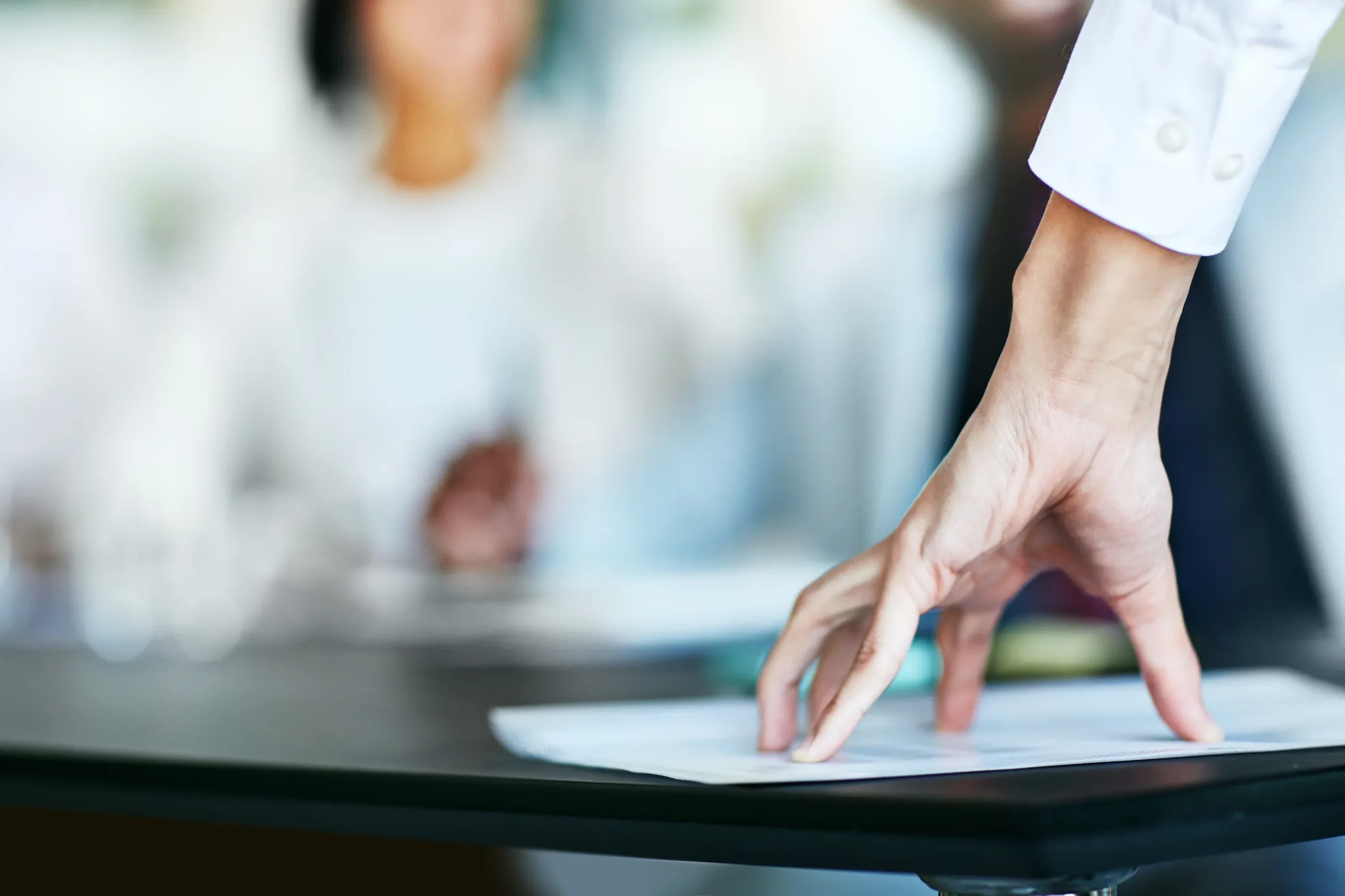 Gros plan sur une main posée sur un document, sur une table de réunion