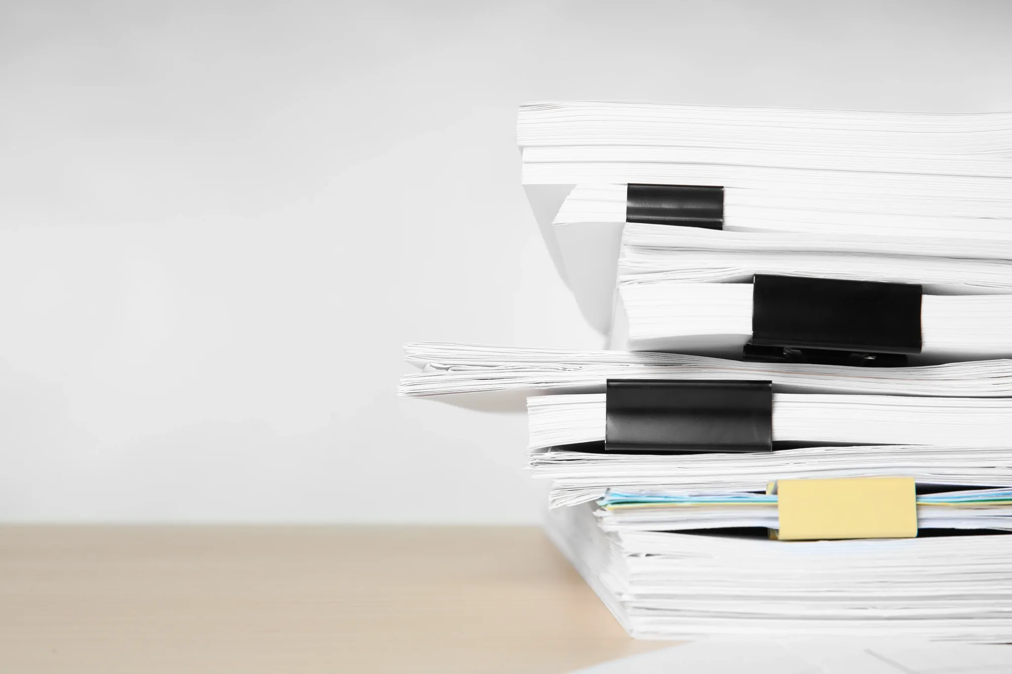 Une pile de documents maintenus par des pinces, sur fond clair